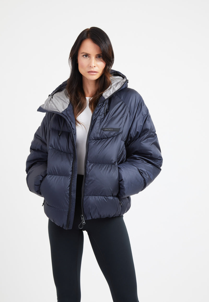 Woman modeling an oversized puffer navy jacket with a modern silhouette and adjustable hood.