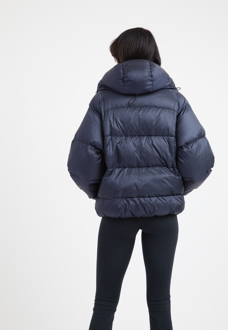 Woman wearing an oversized puffer navy jacket with a hood, showcasing the back view.