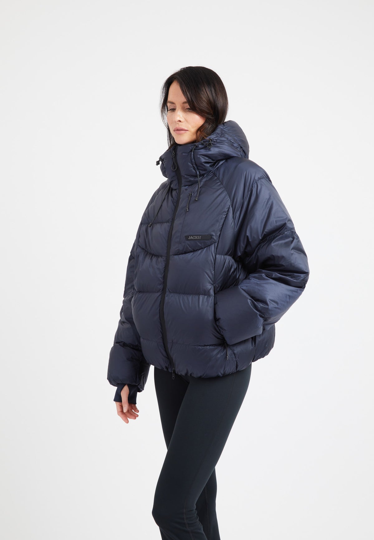 Model wearing an oversized puffer navy jacket featuring adjustable hood and fleece lined pockets.