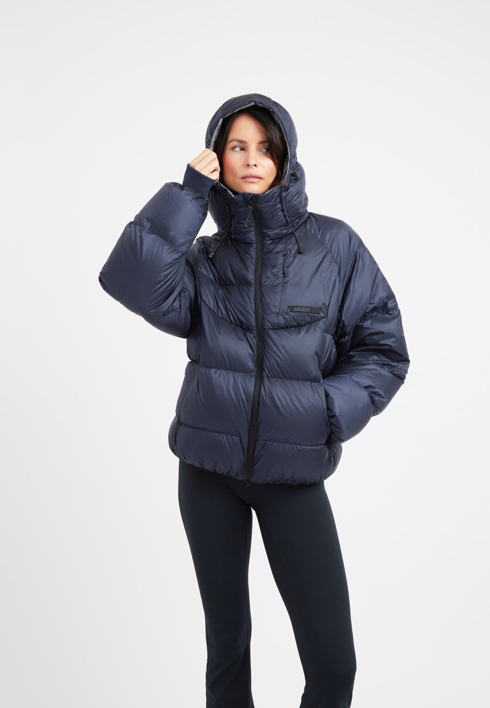 Woman wearing an oversized puffer navy jacket with a hood and zipper, showcasing modern design and comfort.
