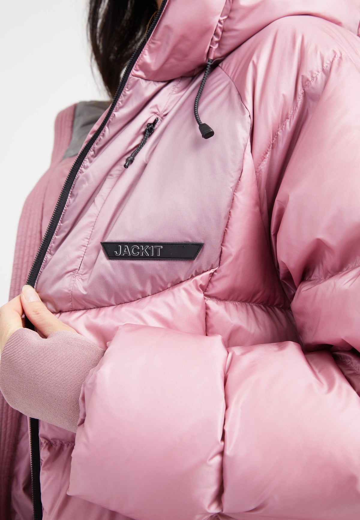 Close-up of a woman wearing a pink oversized puffer jacket with adjustable hood and RDS Certified Down fill.