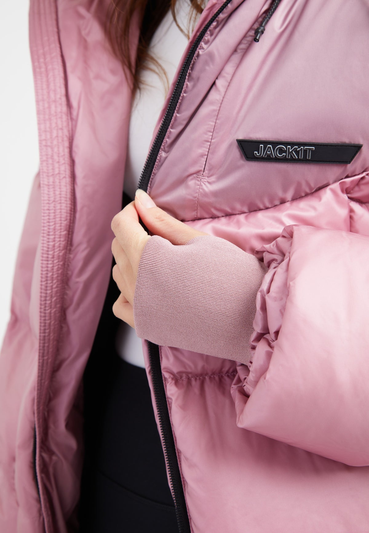 Detail of a woman wearing a pink oversized puffer jacket with an adjustable hood and fabric storm cuffs.