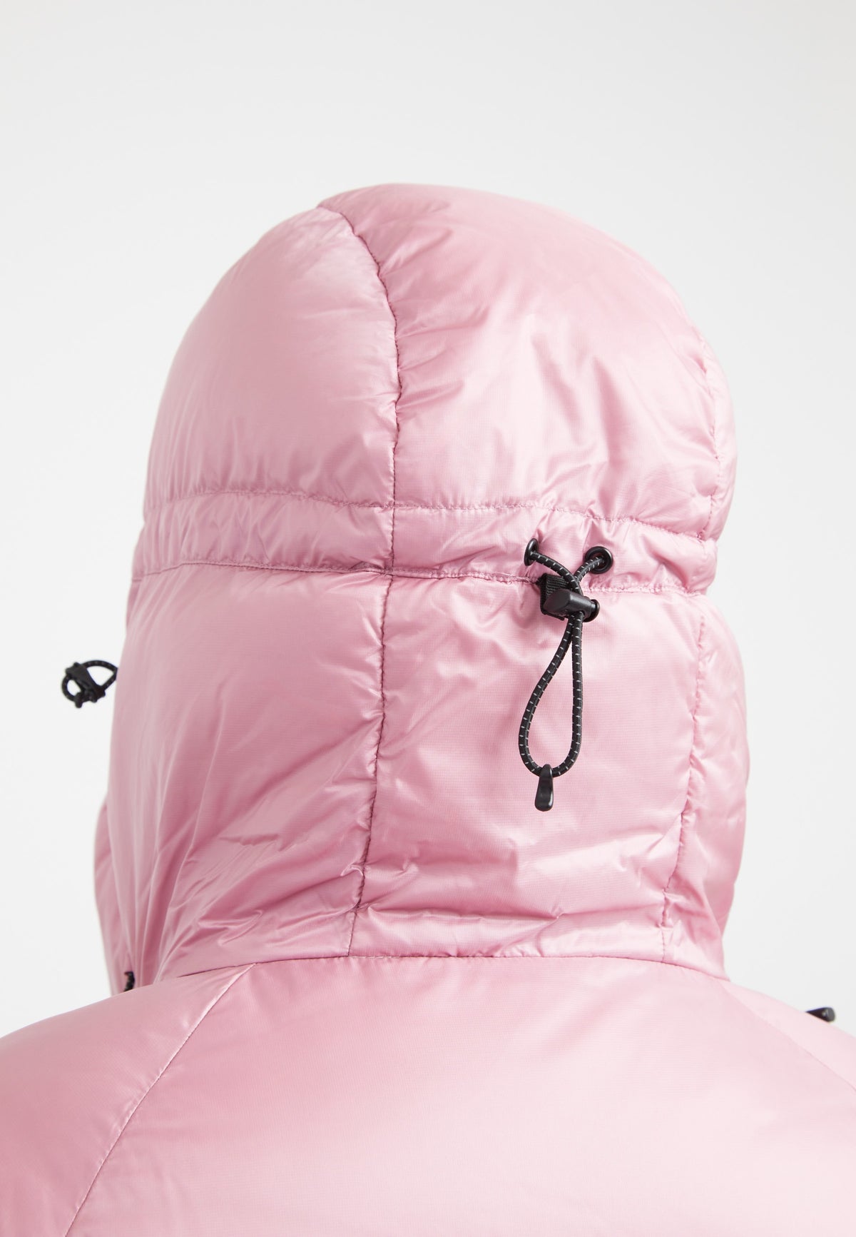 Back view of pink oversized puffer jacket featuring an adjustable hood and fabric storm cuffs.