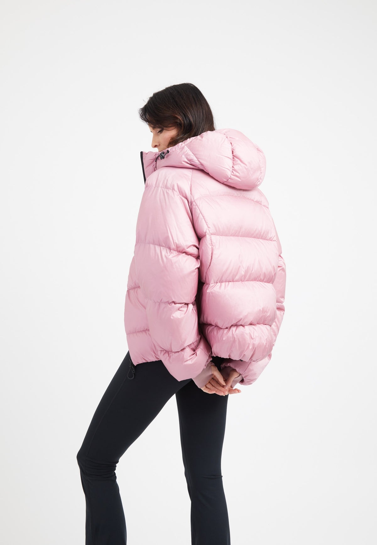 Woman wearing an oversized puffer pink jacket with a hood, showcasing its modern and stylish design.
