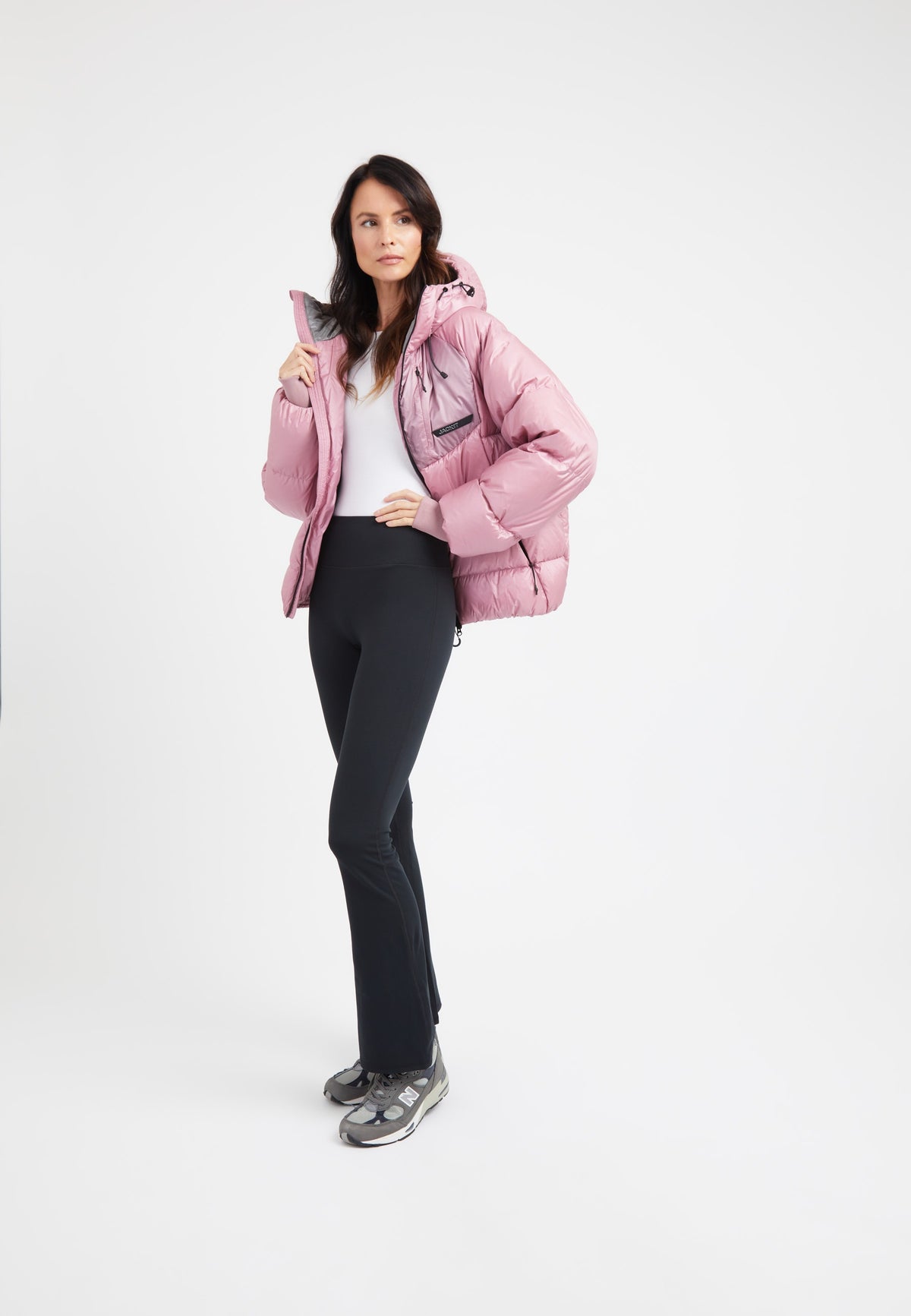 Model wearing an oversized puffer pink jacket with black leggings, showcasing a modern silhouette.