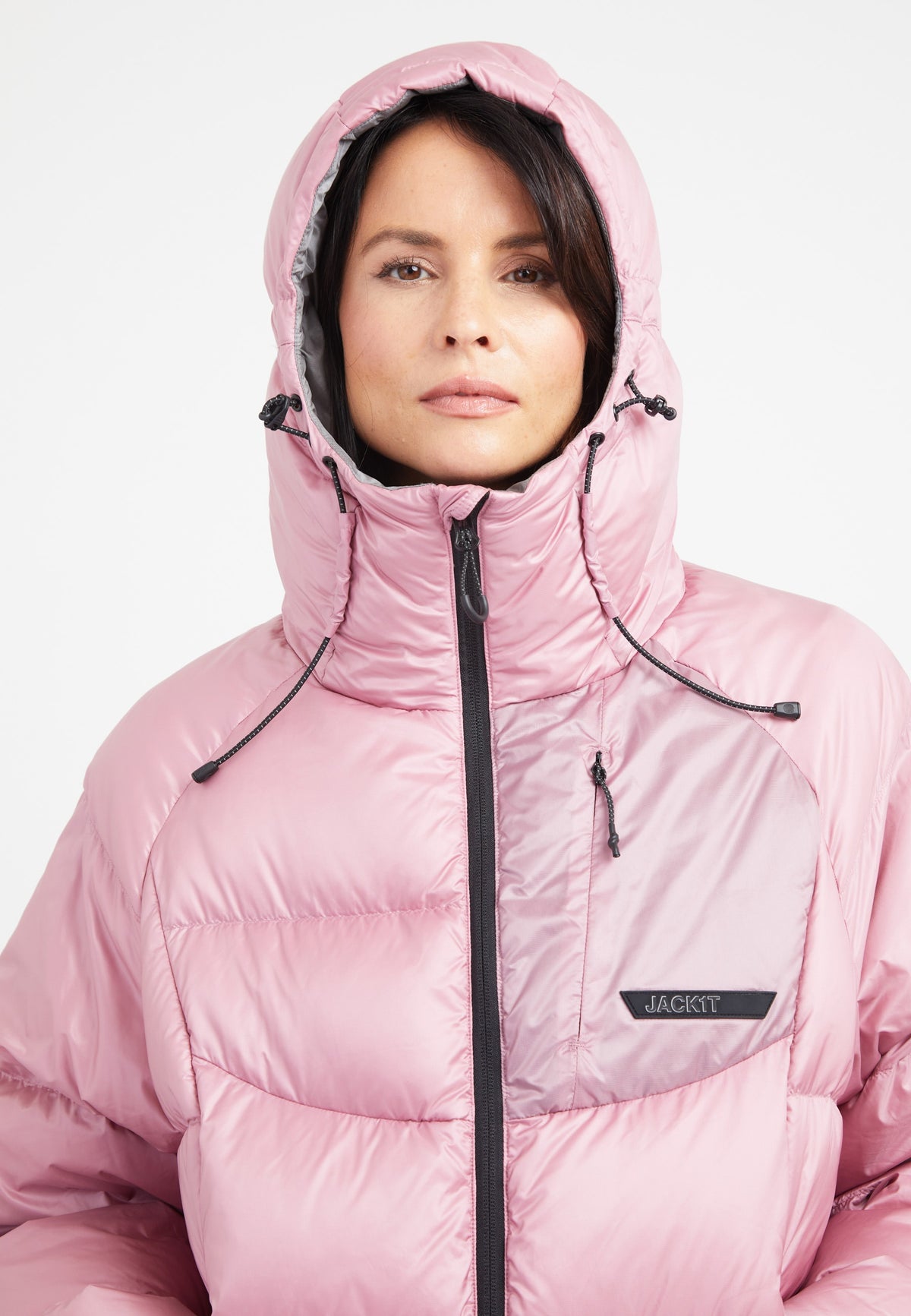 Model wearing a pink oversized puffer jacket with an adjustable hood and fleece-lined pockets.