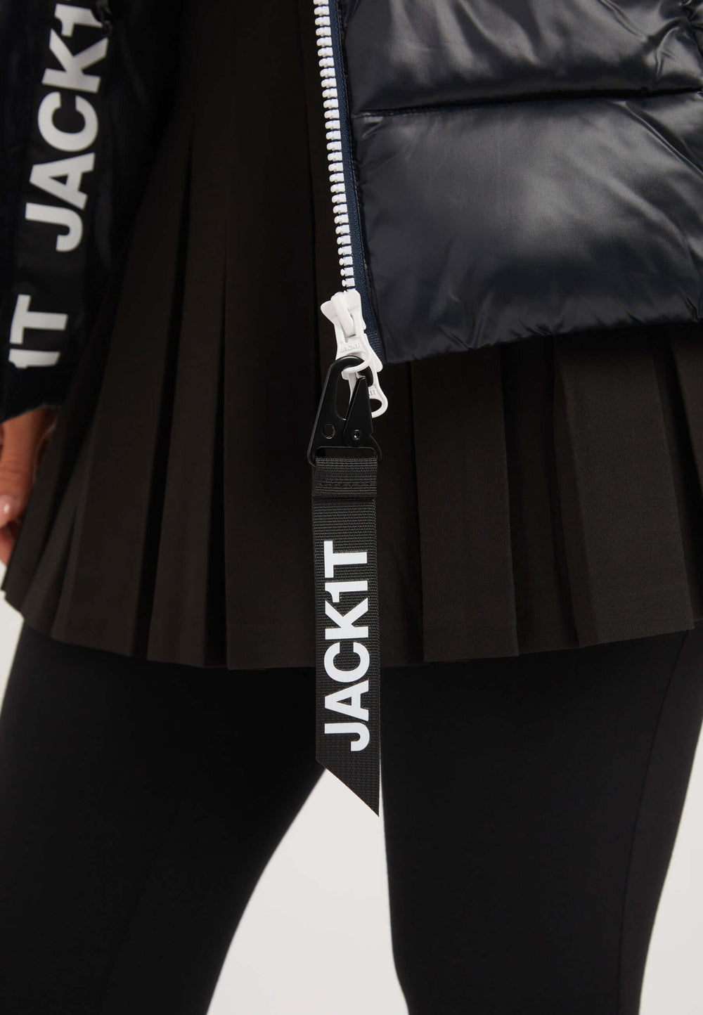 Detail of R4D Tricolore Racer Jacket Black with JACK1T label and black pleated skirt, showcasing the stylish design of this black womens puffer jacket.