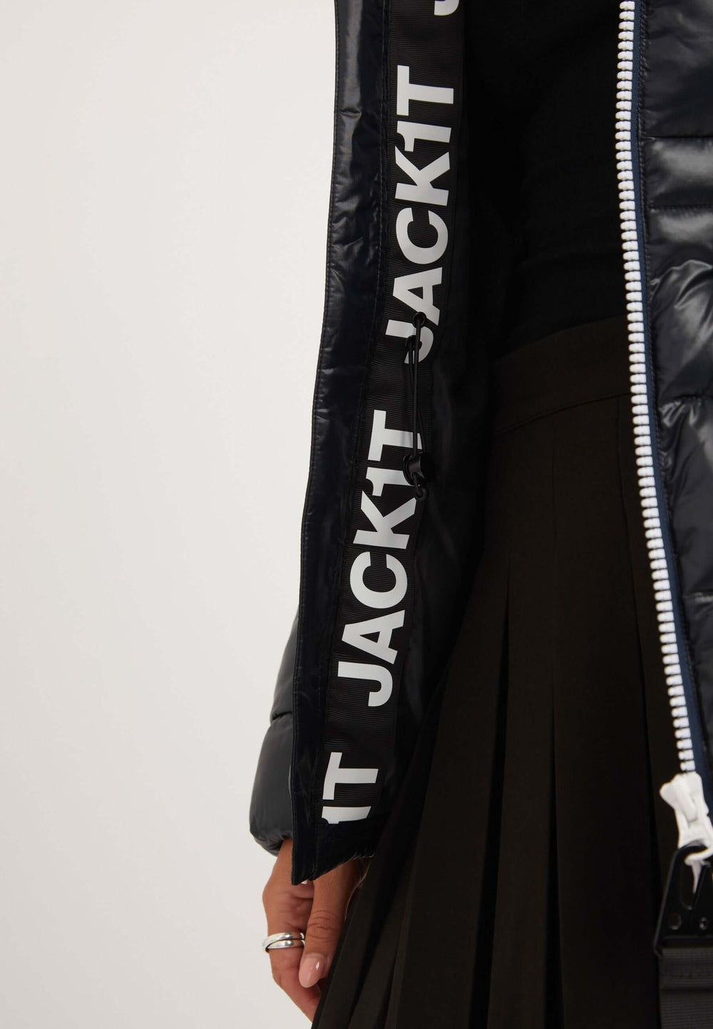 Close-up of black womens puffer jacket showcasing the lettering and zipper detail on the sleeve.