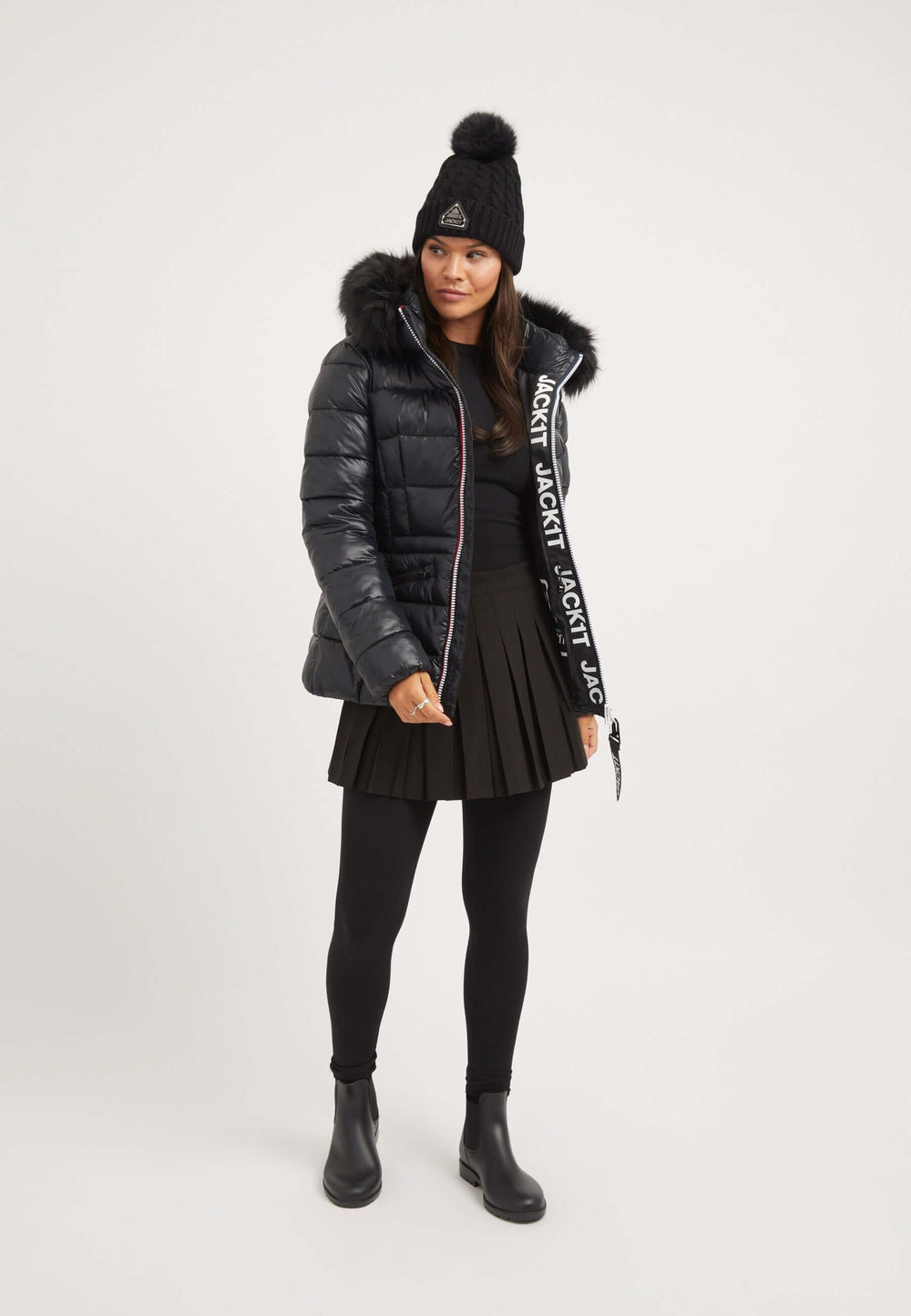 Model wearing the R4D Tricolore Racer Jacket Black with a black womens puffer jacket, fitted skirt, and beanie.